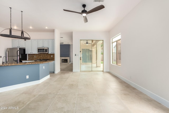 kitchen featuring stainless steel appliances, decorative backsplash, ceiling fan, and white cabinets