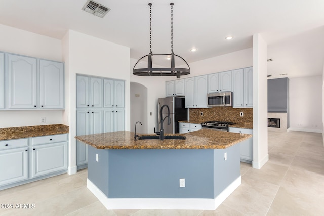 kitchen featuring a center island with sink, stainless steel appliances, decorative backsplash, and light tile patterned flooring