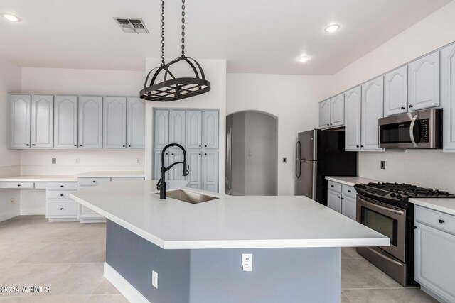 kitchen featuring appliances with stainless steel finishes, plenty of natural light, a kitchen island with sink, and sink