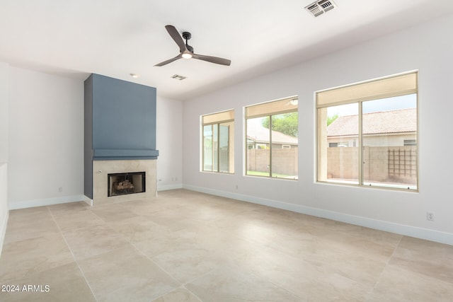 unfurnished living room featuring ceiling fan, light tile patterned floors, and a high end fireplace