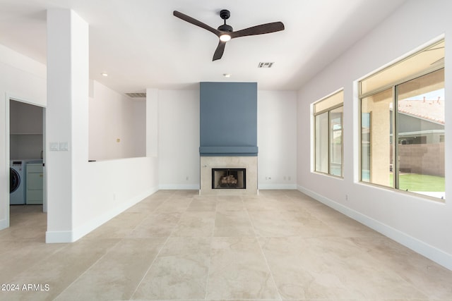 unfurnished living room with washer / clothes dryer, light tile patterned floors, ceiling fan, and a tile fireplace