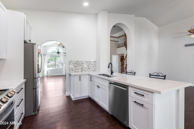 kitchen featuring dark wood-type flooring, white cabinets, kitchen peninsula, stainless steel appliances, and sink