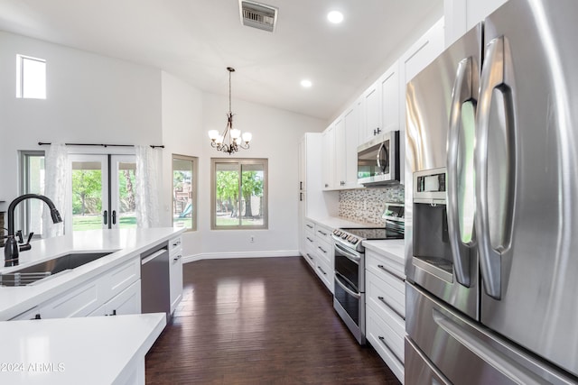 kitchen featuring appliances with stainless steel finishes, hanging light fixtures, white cabinetry, dark hardwood / wood-style floors, and sink