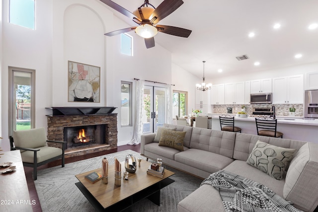 living room with a stone fireplace, hardwood / wood-style flooring, ceiling fan with notable chandelier, and a wealth of natural light