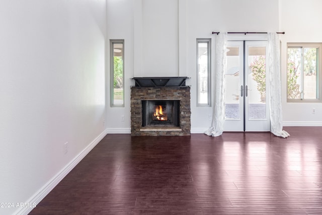 unfurnished living room with french doors, dark wood-type flooring, and a healthy amount of sunlight