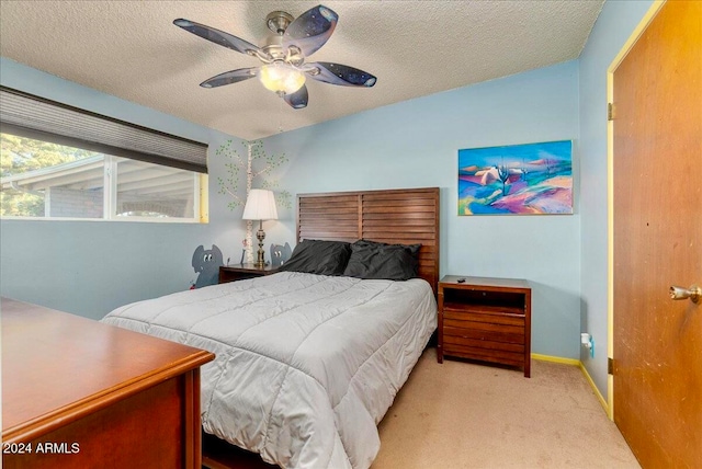 carpeted bedroom featuring ceiling fan and a textured ceiling