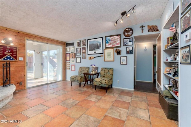 living area with a textured ceiling and wood walls