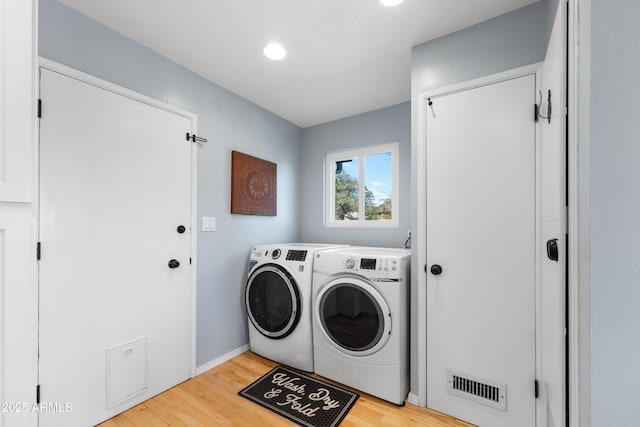 clothes washing area featuring washing machine and clothes dryer and light hardwood / wood-style flooring