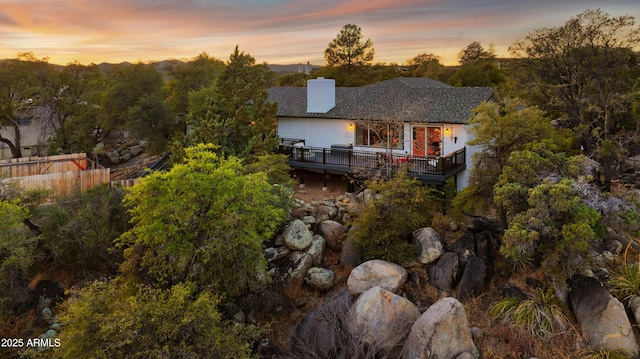 back house at dusk with a wooden deck