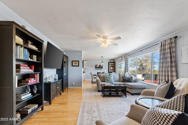 living room with a textured ceiling, light hardwood / wood-style flooring, and ceiling fan