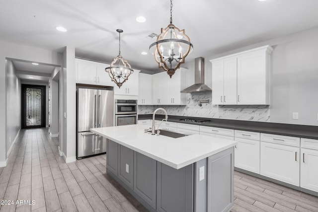 kitchen featuring wall chimney exhaust hood, an inviting chandelier, backsplash, decorative light fixtures, and appliances with stainless steel finishes