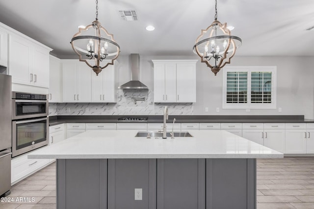 kitchen featuring hanging light fixtures, a chandelier, wall chimney range hood, and sink