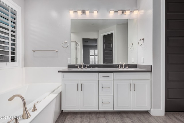 bathroom featuring wood-type flooring, vanity, and a tub to relax in