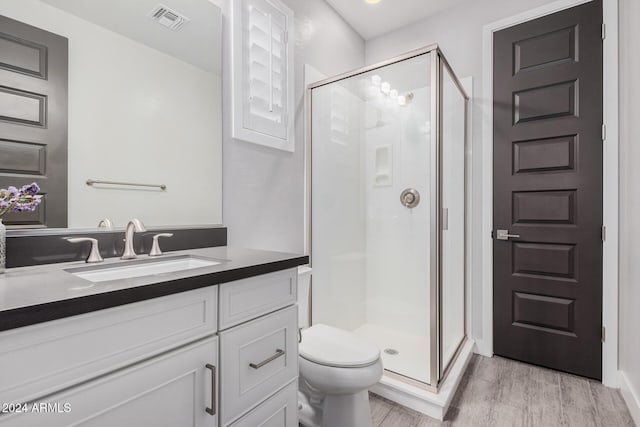 bathroom featuring vanity, toilet, a shower with shower door, and wood-type flooring