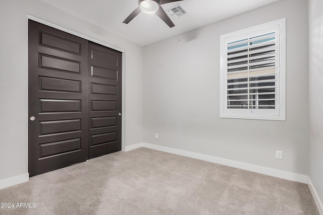 empty room featuring ceiling fan and light colored carpet