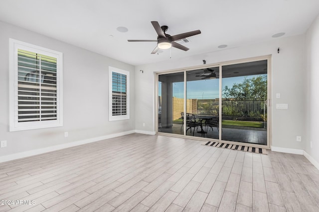 empty room with ceiling fan and light hardwood / wood-style flooring