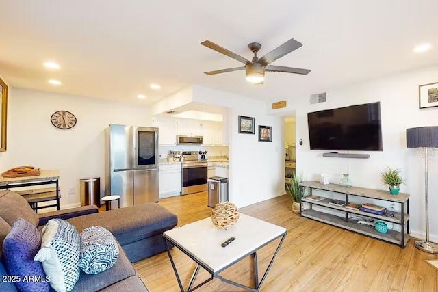 living room featuring a ceiling fan, light wood finished floors, and recessed lighting