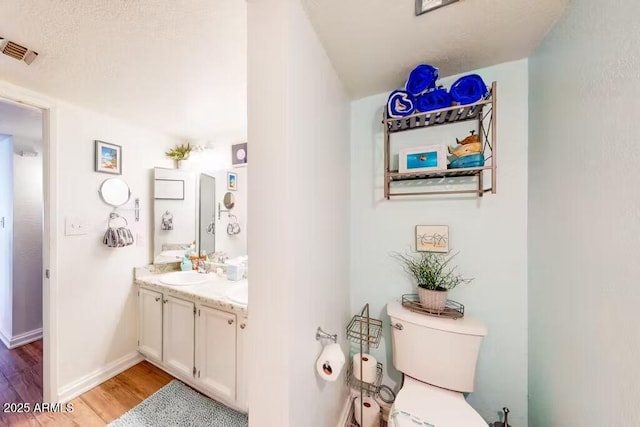bathroom featuring wood finished floors, toilet, vanity, and baseboards