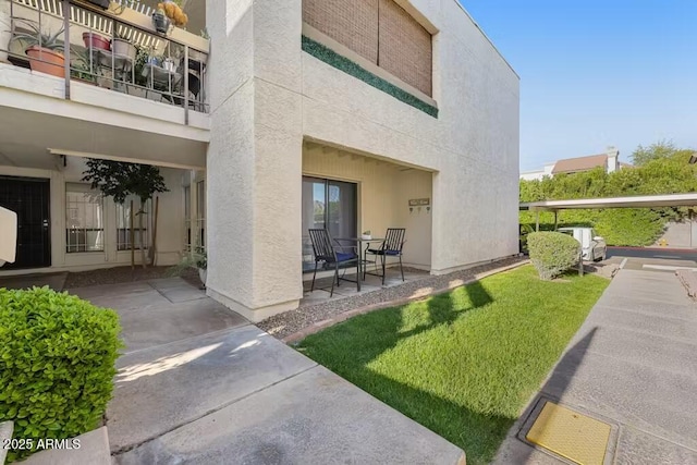 back of house featuring stucco siding, a patio, and a yard