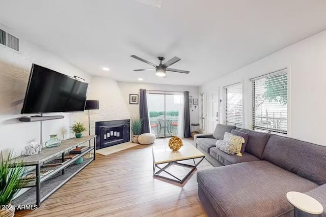 living area with wood finished floors, ceiling fan, recessed lighting, and a large fireplace