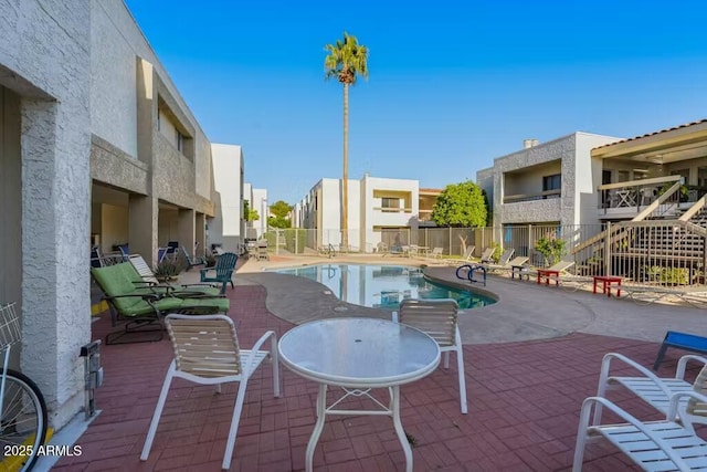 community pool featuring fence, a patio area, and a residential view