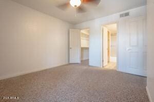 unfurnished bedroom featuring ceiling fan, a walk in closet, a closet, and carpet floors