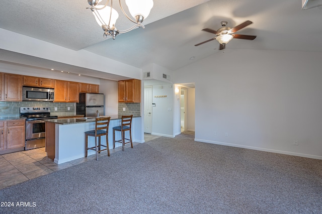 kitchen featuring lofted ceiling, decorative light fixtures, a center island, appliances with stainless steel finishes, and a kitchen breakfast bar