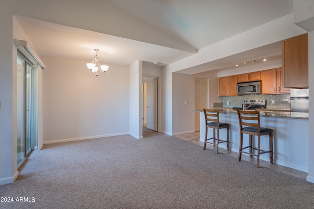 kitchen featuring lofted ceiling, stainless steel appliances, tasteful backsplash, kitchen peninsula, and a breakfast bar area