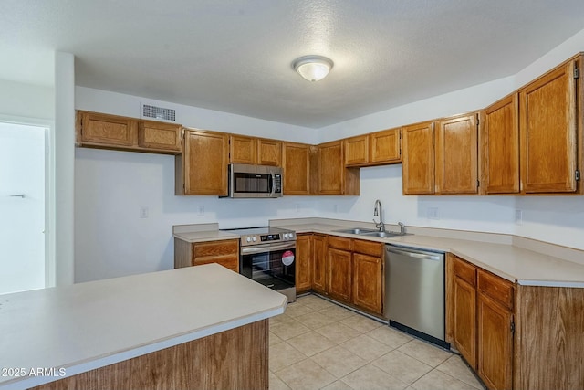 kitchen with sink, light tile patterned flooring, a textured ceiling, and appliances with stainless steel finishes