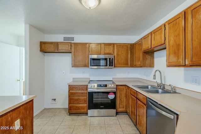 kitchen with sink, light tile patterned flooring, and stainless steel appliances