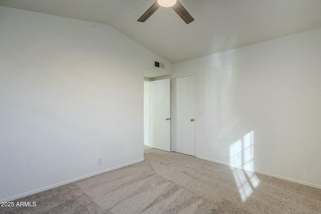 carpeted spare room with ceiling fan and vaulted ceiling