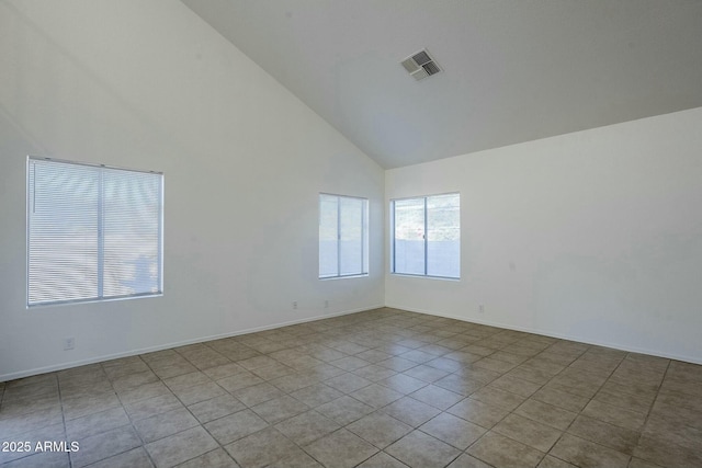 empty room with light tile patterned floors and high vaulted ceiling