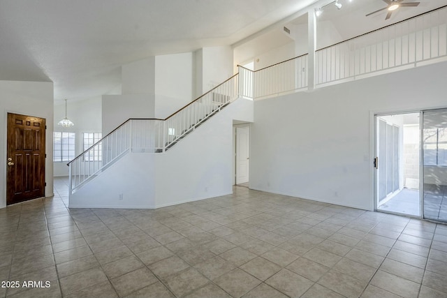 unfurnished living room featuring ceiling fan with notable chandelier, light tile patterned floors, and high vaulted ceiling