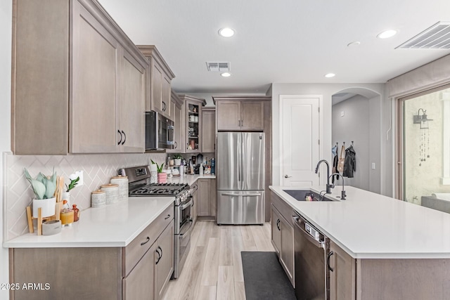 2499 S Entwistle St, Gilbert, AZ 85295 - kitchen with appliances with stainless steel finishes, a sink, glass insert cabinets, light countertops, and backsplash