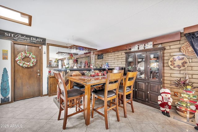 tiled dining room featuring brick wall and indoor bar