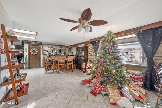 tiled dining room with ceiling fan, brick wall, and a textured ceiling