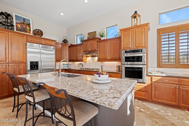 kitchen with a kitchen bar, sink, an island with sink, and appliances with stainless steel finishes