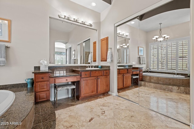 bathroom featuring tiled bath, plenty of natural light, vanity, and a notable chandelier