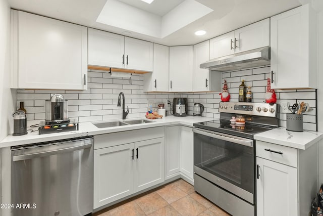 kitchen with appliances with stainless steel finishes, tasteful backsplash, sink, light tile patterned floors, and white cabinetry