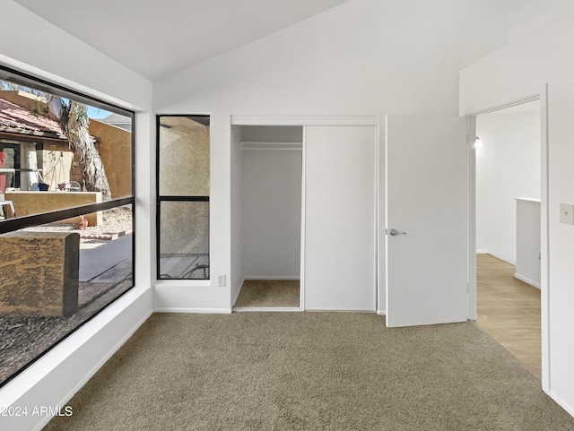 unfurnished bedroom featuring lofted ceiling, light carpet, and a closet