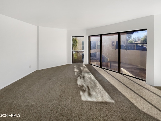 unfurnished room featuring dark colored carpet