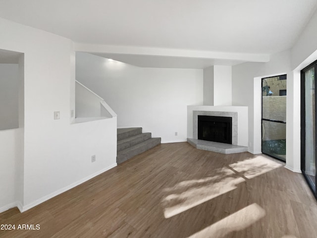 unfurnished living room featuring a tiled fireplace and wood-type flooring