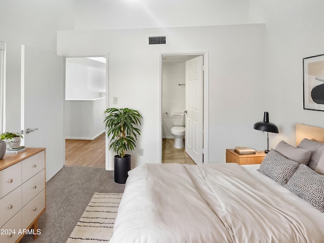 bedroom featuring connected bathroom and light colored carpet