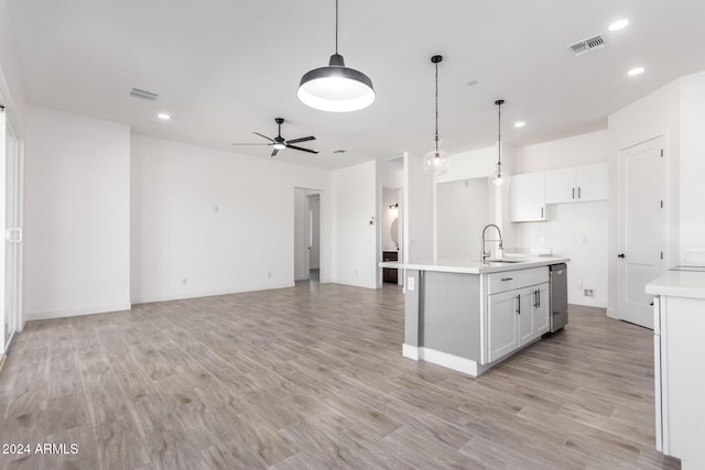 kitchen with white cabinetry, light hardwood / wood-style flooring, an island with sink, and decorative light fixtures