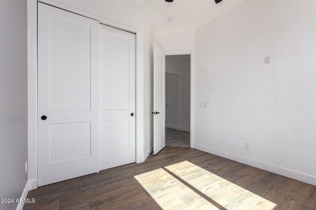 unfurnished bedroom featuring a closet and dark wood-type flooring