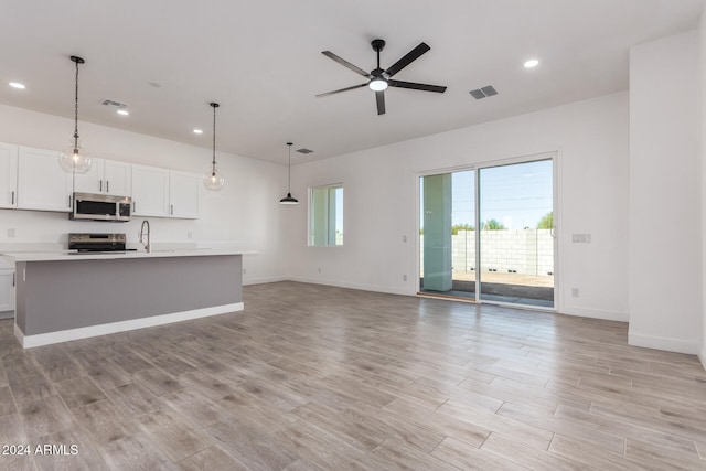 unfurnished living room featuring ceiling fan and light wood-type flooring