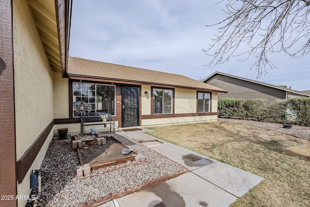 entrance to property with a lawn and stucco siding