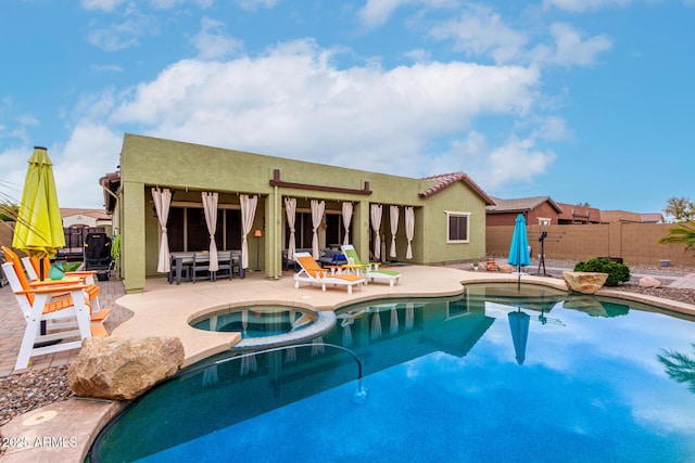 view of swimming pool with a patio area, a pool with connected hot tub, and fence