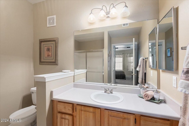 bathroom with a shower with shower door, vanity, and toilet