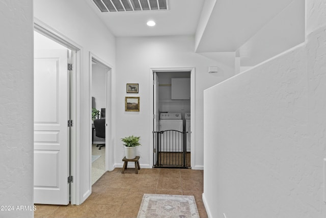 hall with independent washer and dryer and light tile patterned floors